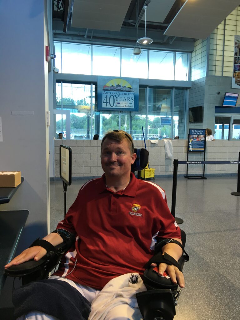 Wheelchair user seated in a bright airport or transit terminal.